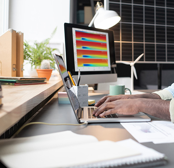 person typing on a laptop at a desk with a monitor displaying graphs and charts seven innovative ideas for productivity